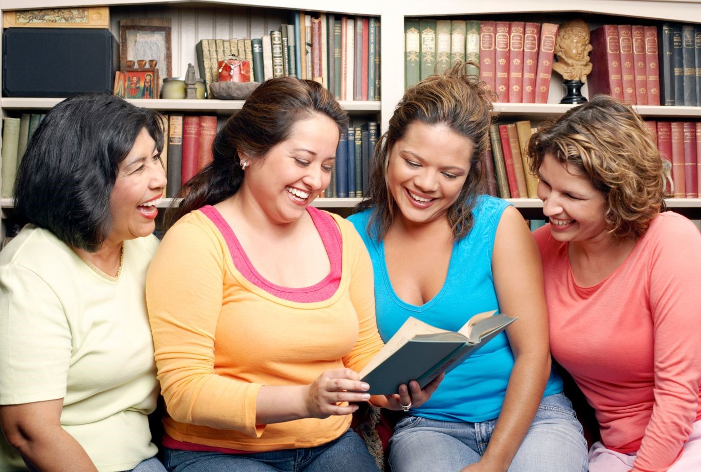 Four Women sitting around looking at book